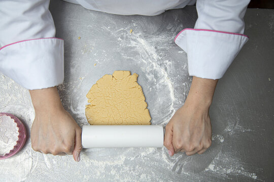 woman's hands with a baking roller kneading flour for cookies zenithal view