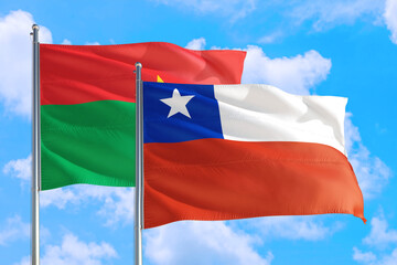 Fototapeta na wymiar Chile and Burkina Faso national flag waving in the windy deep blue sky. Diplomacy and international relations concept.