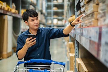 man looking at his mobile phone and shopping in warehouse store