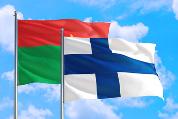 Finland and Burkina Faso national flag waving in the windy deep blue sky. Diplomacy and international relations concept.