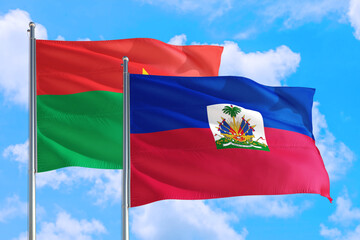 Haiti and Burkina Faso national flag waving in the windy deep blue sky. Diplomacy and international relations concept.