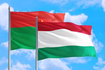 Hungary and Burkina Faso national flag waving in the windy deep blue sky. Diplomacy and international relations concept.