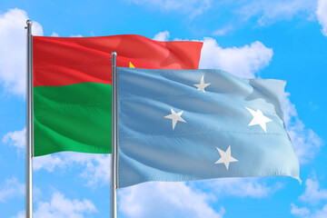 Micronesia and Burkina Faso national flag waving in the windy deep blue sky. Diplomacy and international relations concept.