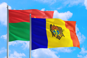 Moldova and Burkina Faso national flag waving in the windy deep blue sky. Diplomacy and international relations concept.