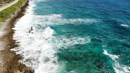 Blue sea wave crashing against rocky stone cliff 