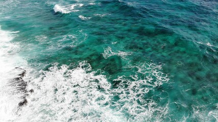Blue sea wave crashing against rocky stone cliff 