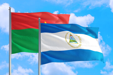 Nicaragua and Burkina Faso national flag waving in the windy deep blue sky. Diplomacy and international relations concept.