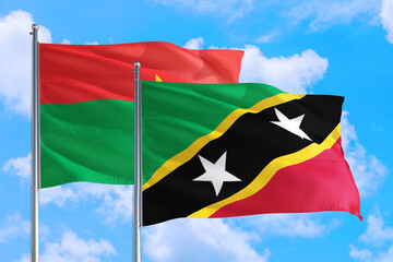 Saint Kitts And Nevis and Burkina Faso national flag waving in the windy deep blue sky. Diplomacy and international relations concept.