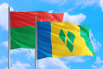 Saint Vincent And The Grenadines and Burkina Faso national flag waving in the windy deep blue sky. Diplomacy and international relations concept.