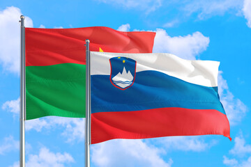Slovenia and Burkina Faso national flag waving in the windy deep blue sky. Diplomacy and international relations concept.