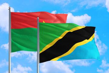 Tanzania and Burkina Faso national flag waving in the windy deep blue sky. Diplomacy and international relations concept.