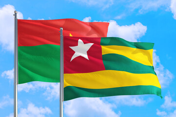 Togo and Burkina Faso national flag waving in the windy deep blue sky. Diplomacy and international relations concept.