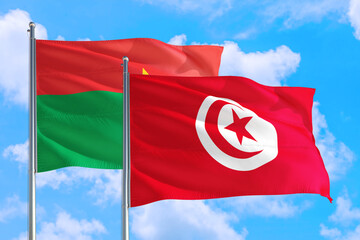 Tunisia and Burkina Faso national flag waving in the windy deep blue sky. Diplomacy and international relations concept.