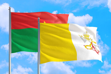 Vatican City and Burkina Faso national flag waving in the windy deep blue sky. Diplomacy and international relations concept.