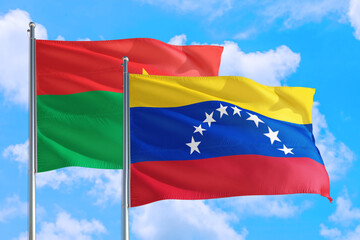 Venezuela and Burkina Faso national flag waving in the windy deep blue sky. Diplomacy and international relations concept.