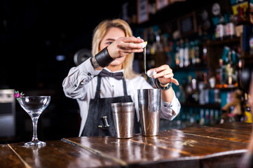 Sweet woman barkeeper makes a show creating a cocktail in pub