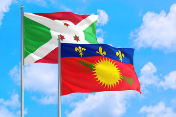Guadeloupe and Burundi national flag waving in the windy deep blue sky. Diplomacy and international relations concept.