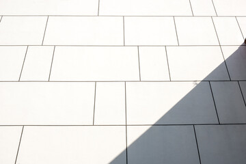 abstract background. Minimalist Detail Of White Paneled Contemporary Building Wall, With Bright Sunlight And Hard Shadow, Backgrounds, Textures. Stock Photograph.