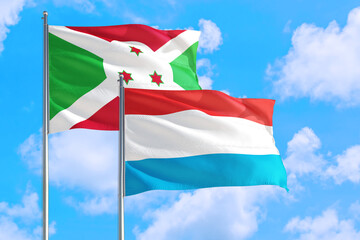 Luxembourg and Burundi national flag waving in the windy deep blue sky. Diplomacy and international relations concept.