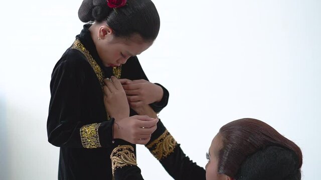 A portrait of a mother tidy up her daughter kebaya javanese traditional clothes
