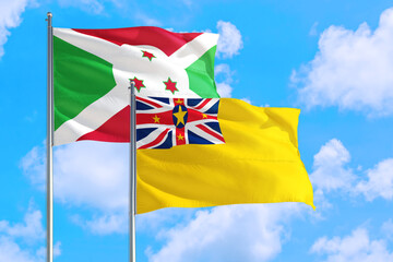 Niue and Burundi national flag waving in the windy deep blue sky. Diplomacy and international relations concept.