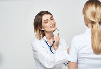 A nurse doctor in a medical gown explains something to a patient in a white T-shirt