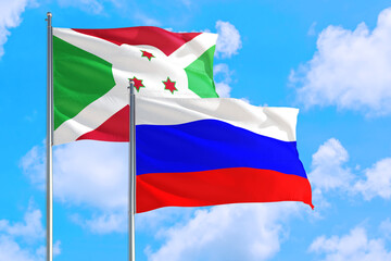 Russia and Burundi national flag waving in the windy deep blue sky. Diplomacy and international relations concept.