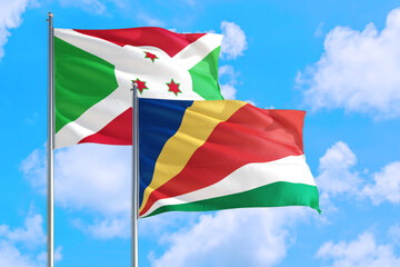 Seychelles and Burundi national flag waving in the windy deep blue sky. Diplomacy and international relations concept.