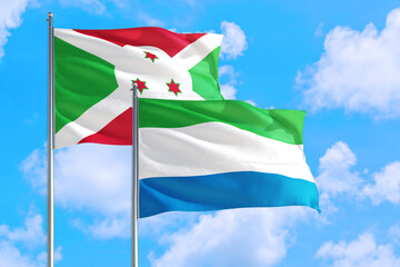 Sierra Leone and Burundi national flag waving in the windy deep blue sky. Diplomacy and international relations concept.