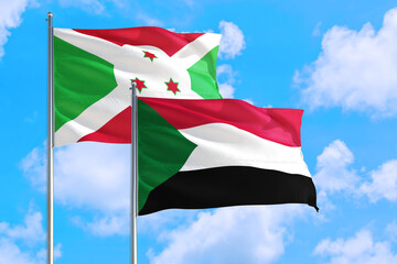 Sudan and Burundi national flag waving in the windy deep blue sky. Diplomacy and international relations concept.