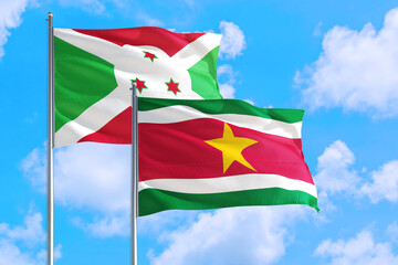 Suriname and Burundi national flag waving in the windy deep blue sky. Diplomacy and international relations concept.