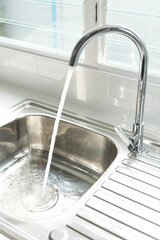 Water flows from a faucet into the sink of the kitchen.