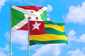 Togo and Burundi national flag waving in the windy deep blue sky. Diplomacy and international relations concept.