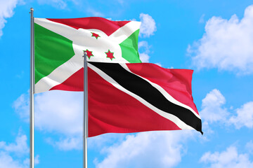 Trinidad And Tobago and Burundi national flag waving in the windy deep blue sky. Diplomacy and international relations concept.