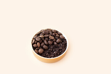 gold round cosmetic jar with coffee scrub large granules and coffee beans on clean soft beige background, selective focus