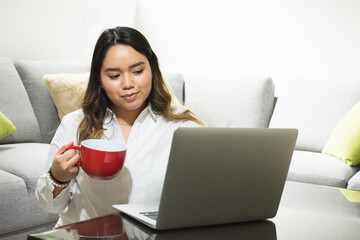 Woman holding a mug and working on a computer