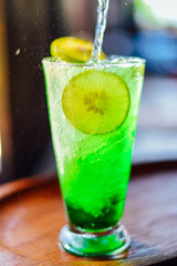 green juice water whit soda and lemon in glass on wood table at cafe. Summer  drink
