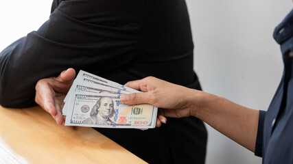 Businessman reciving money United States Dollars bills to corruption from his partner in business at working desk - bribery concept.
