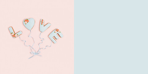 Painted gingerbread in shape of word love as balloons connected by ribbon on pink background witn copy space for your text. Love romance concept.
