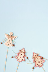 Christmas decorations, wooden figure of an angel and Christmas tree, New Year toys on blue colored paper background. Flat lay. Top view.