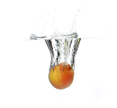 Closeup shot of fresh grayfruit falling into the water on a white background