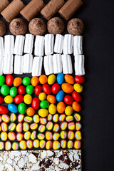 Various colored sweets, candies, marshmallows, chocolate on black desk copy space. Food background