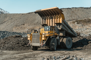 The mining dump truck unloads ore at the gold mining site.