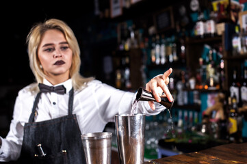 Portrait of girl bartender makes a show creating a cocktail on the bar
