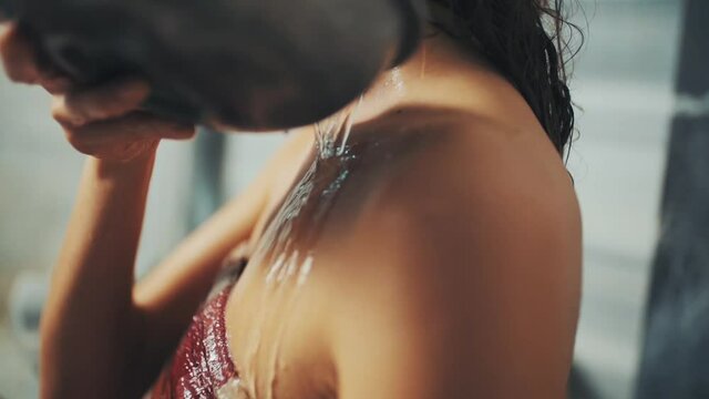 woman in loincloth pours water bowl over her shoulder in Turkish bath. close up.