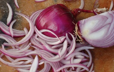 Cebolla morada en trozo y rebanada sobre platón de barro