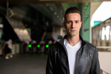 Handsome young Italian man with undercut wearing black leather jacket outdoors