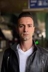 Face of handsome young Italian man with undercut wearing black leather jacket outdoors