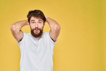 Bearded man white t-shirt emotions gestures with hands fun yellow background