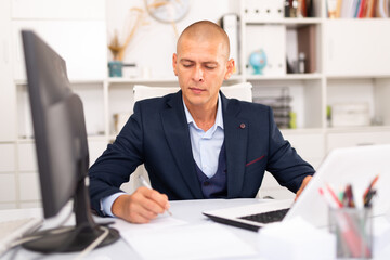 Fototapeta na wymiar Successful businessman working with papers and laptop in office
